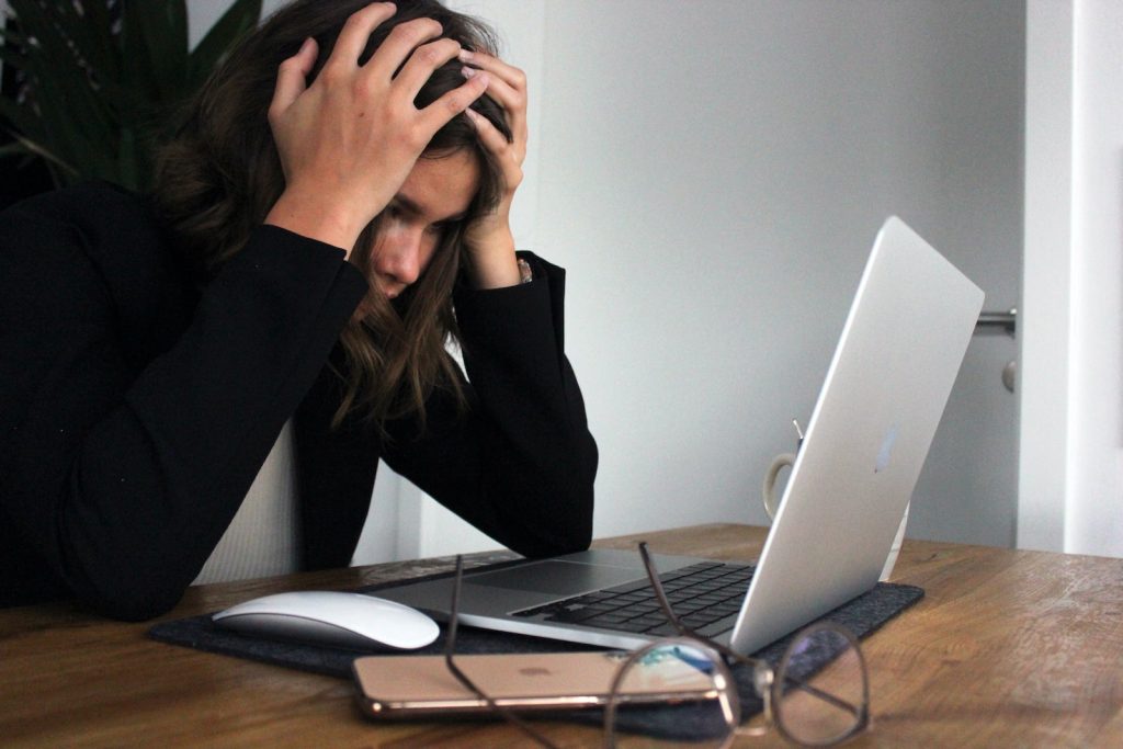 woman looking at her laptop screen showing signs of stress and its impact on her mental health